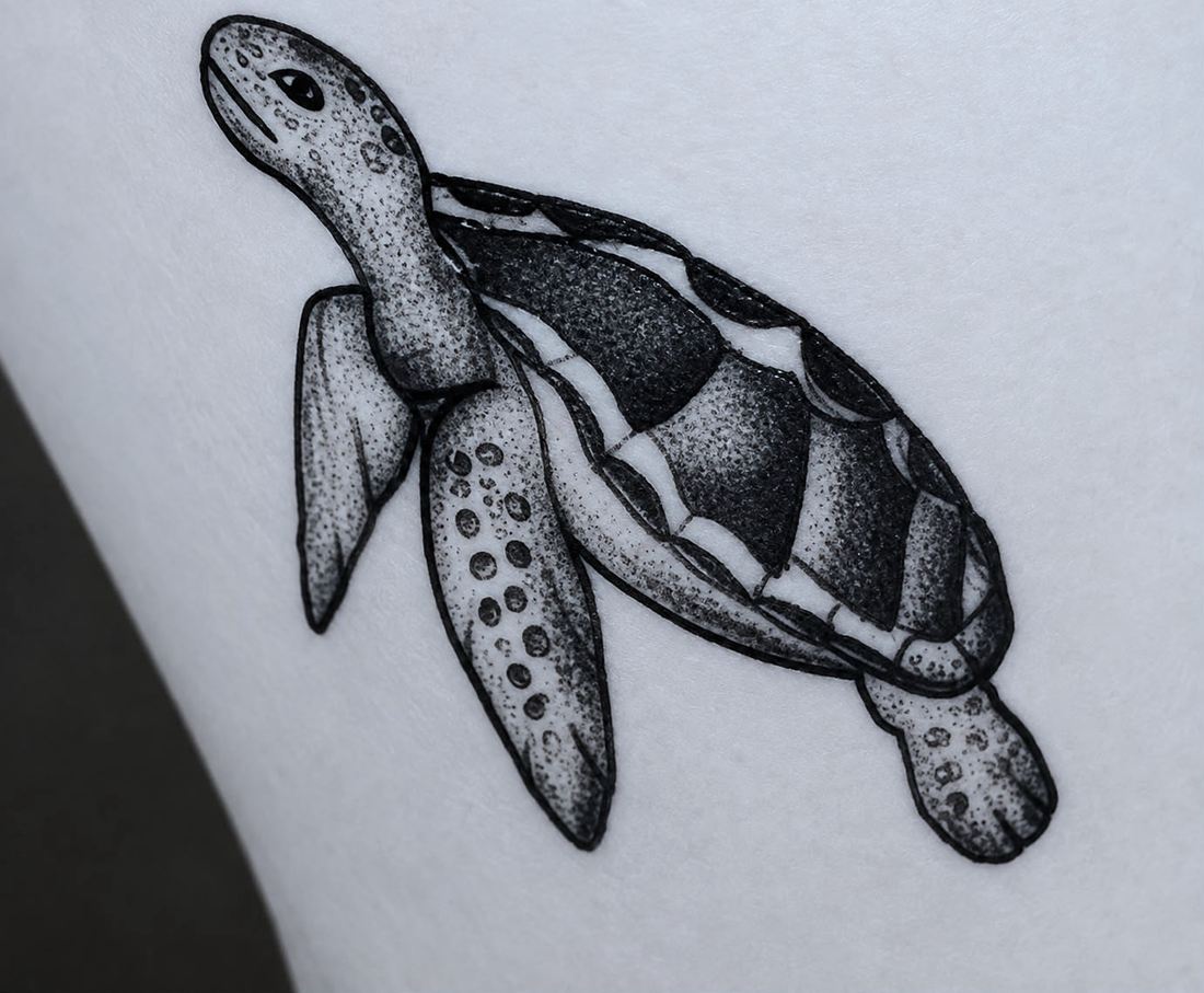 Tatuaje en el brazo. Una tortuga marina nadando, con el caparazon relleno a base de puntos.
