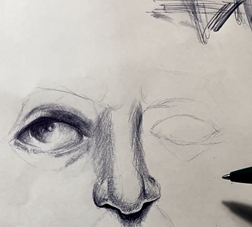 Boligrafo sobre papel. Medio rostro: un ojo terminado, con pestanas y brillo, y el otro solo apuntado a lapiz. Al lado, sobre el papel, el boligrafo verde.